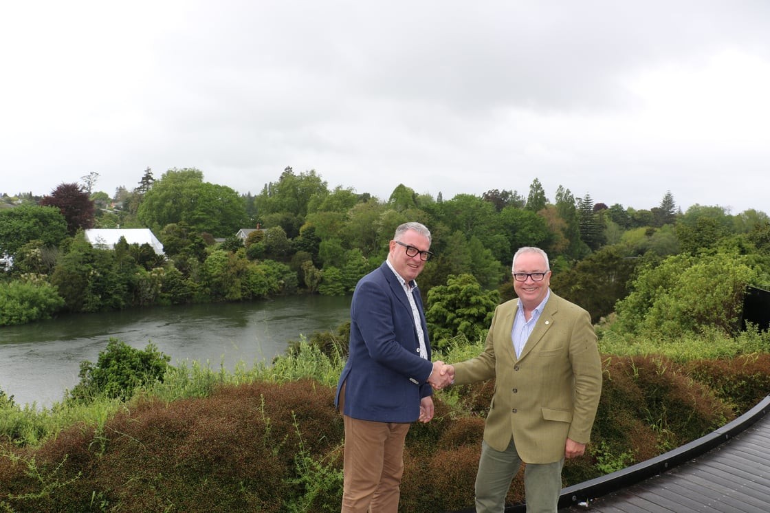 Peter Winder shaking hands with Kevin Lavery overlooking the Waikato River